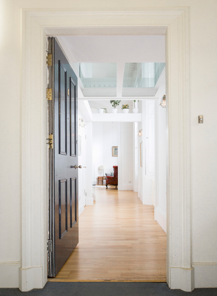 This is an example of a small contemporary hallway in Edinburgh with white walls and medium hardwood flooring.