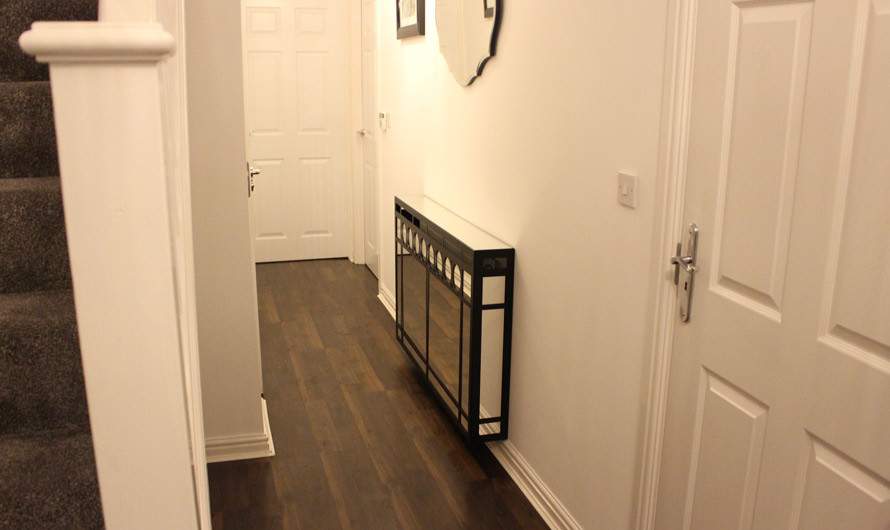 This is an example of a contemporary hallway in London with white walls, dark hardwood flooring and a single front door.