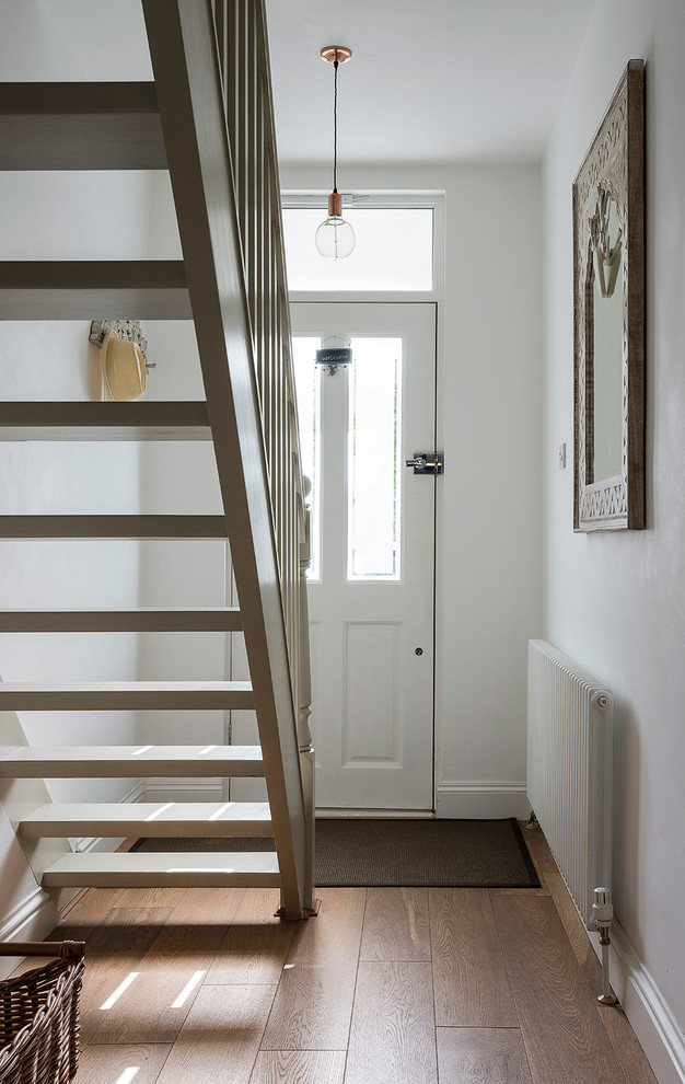 Esempio di un corridoio chic con pareti bianche, pavimento in legno massello medio, una porta singola e una porta bianca