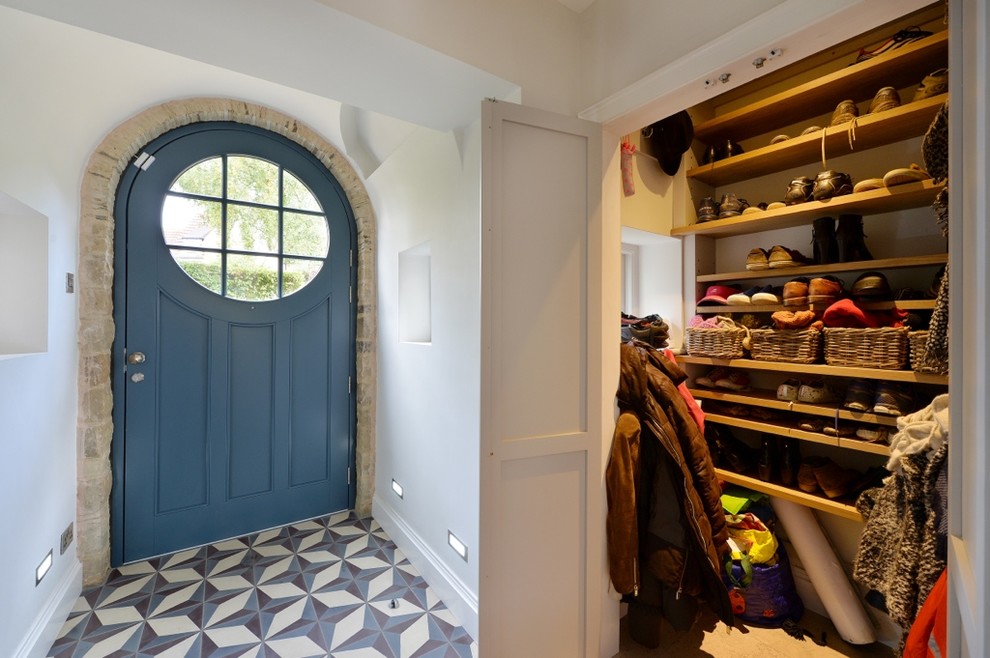 Diseño de entrada de estilo de casa de campo con paredes blancas, puerta simple, puerta azul y suelo multicolor