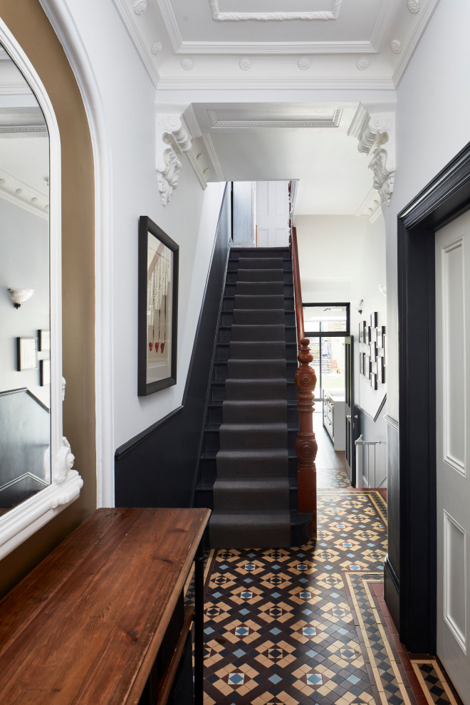 ロンドンにある高級な広いヴィクトリアン調のおしゃれな玄関ドア (磁器タイルの床、グレーのドア、マルチカラーの床、レンガ壁) の写真