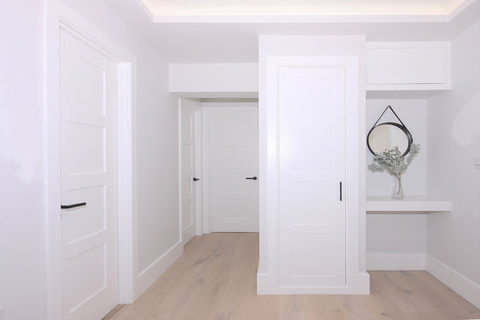 Idee per un piccolo corridoio minimal con pareti grigie, pavimento in legno massello medio, una porta singola, una porta bianca e pavimento bianco