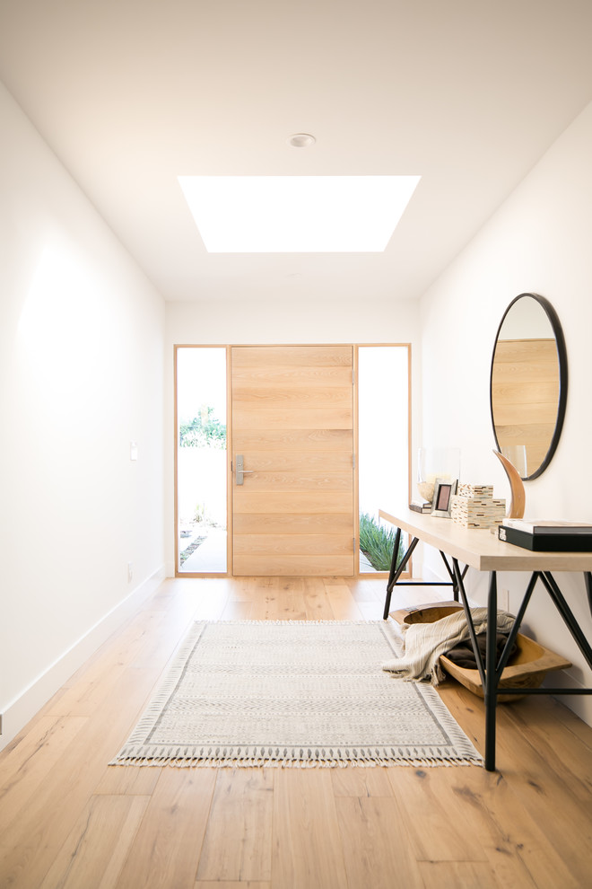 Foto de hall contemporáneo con paredes blancas, suelo de madera clara, puerta simple, puerta de madera clara y suelo beige