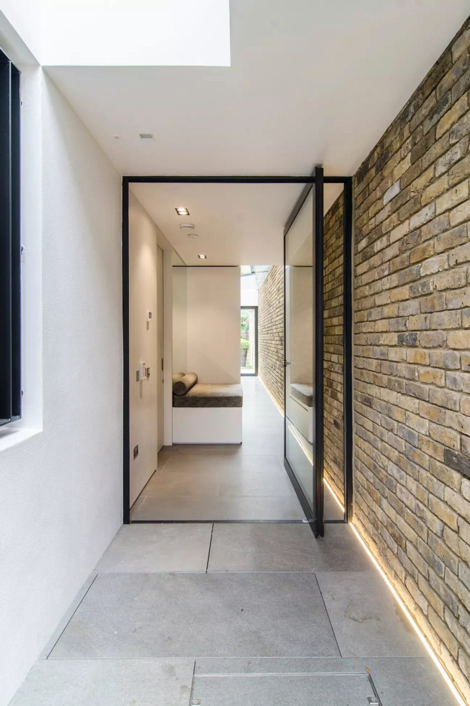 Idées déco pour un grand vestibule contemporain avec un sol en calcaire, une porte pivot, une porte en verre, un sol gris, un plafond voûté et un mur en parement de brique.