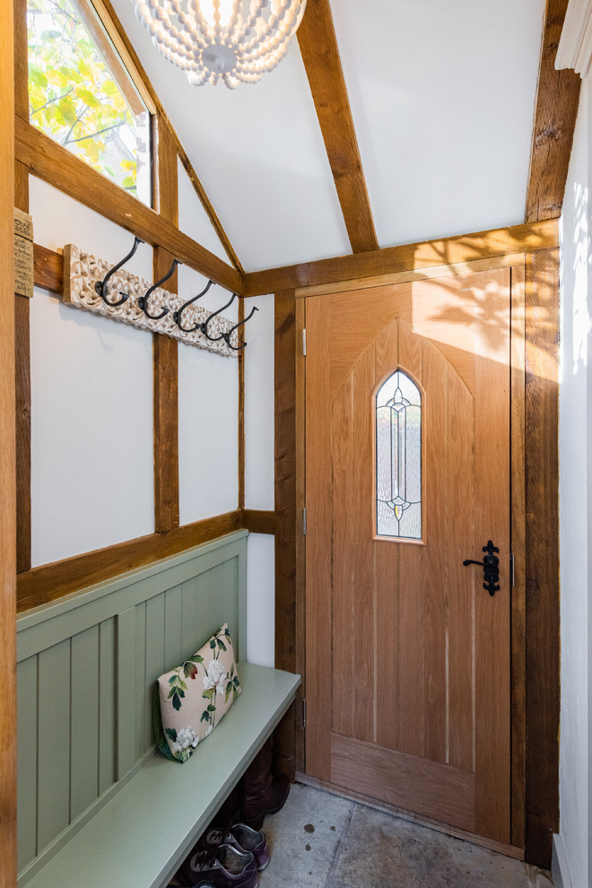 This is an example of a farmhouse entrance in London with white walls, a single front door, a medium wood front door and grey floors.
