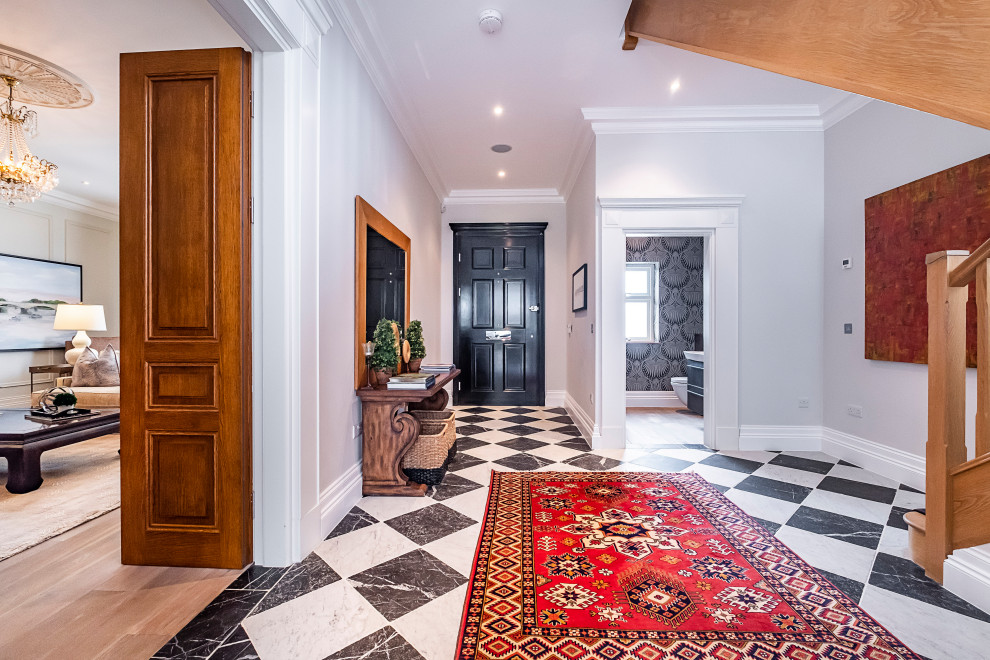他の地域にあるヴィクトリアン調のおしゃれな玄関 (大理石の床、黒い床、ペルシャ絨毯) の写真