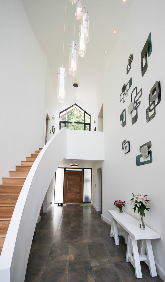 Bild på en funkis foajé, med vita väggar, en enkeldörr, mellanmörk trädörr och grått golv