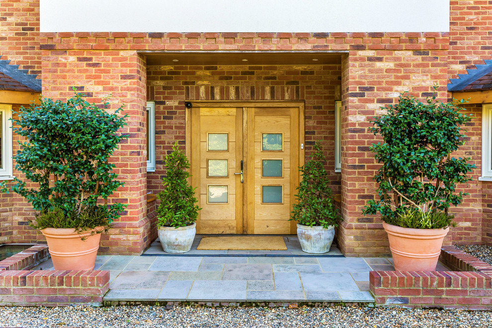 Cette photo montre une porte d'entrée tendance avec une porte double, une porte en bois clair et un sol gris.