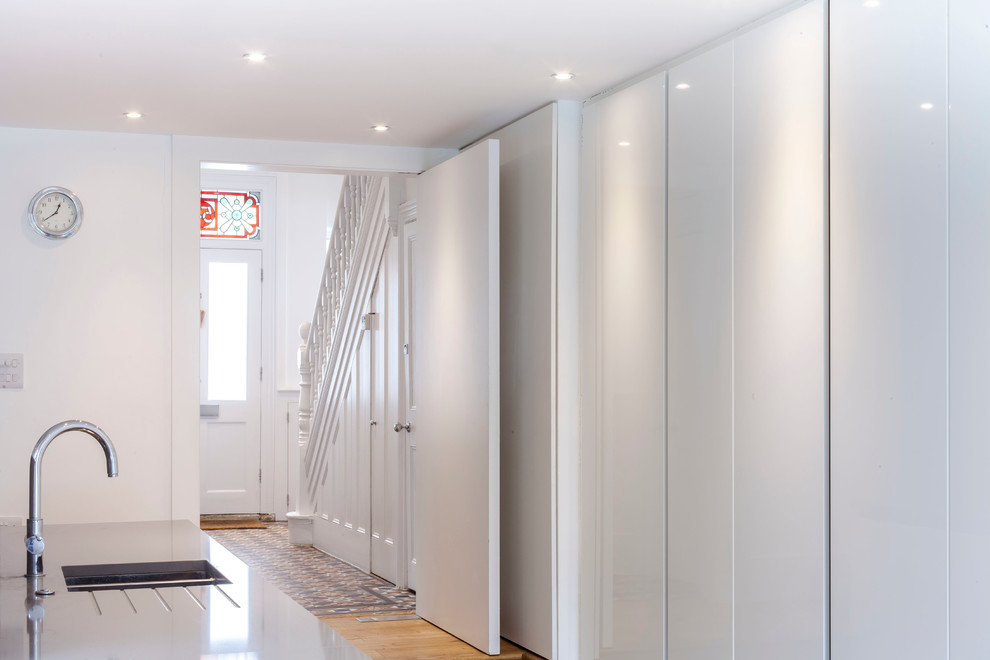 Foto di un corridoio contemporaneo di medie dimensioni con pareti bianche, pavimento in legno massello medio, una porta singola e una porta bianca