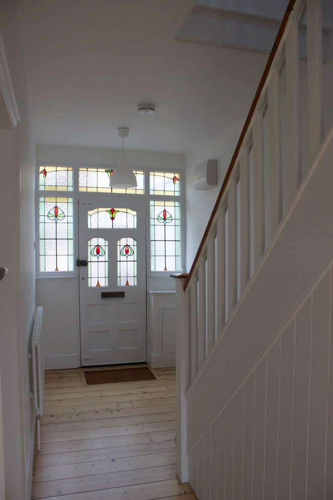 Idée de décoration pour une entrée tradition avec un mur blanc, parquet clair, une porte simple et une porte blanche.