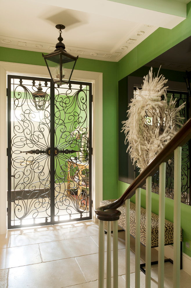 Imagen de entrada bohemia de tamaño medio con paredes verdes, suelo de travertino y puerta metalizada