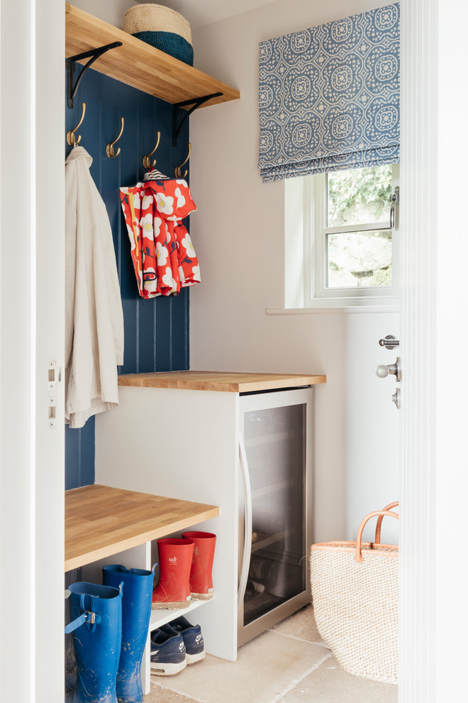 This is an example of a small beach style boot room in Cornwall with blue walls, limestone flooring and beige floors.