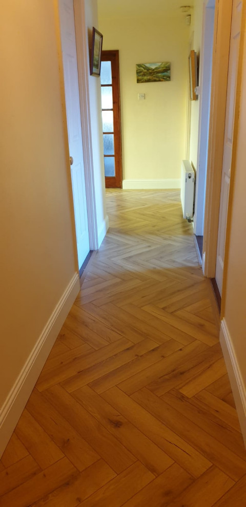 Example of a huge mountain style laminate floor and yellow floor entryway design in Cork with yellow walls and a dark wood front door