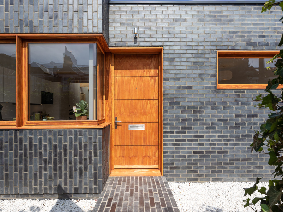 Design ideas for a medium sized contemporary front door in London with grey walls, brick flooring, a single front door, a medium wood front door and grey floors.