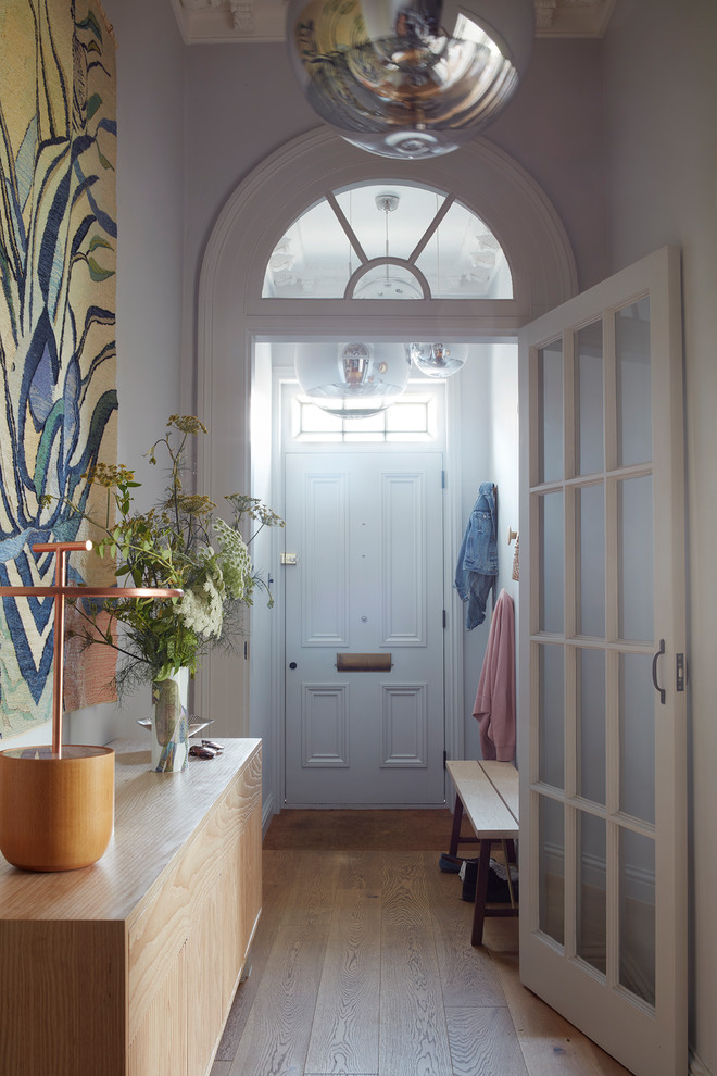 Mid-sized transitional medium tone wood floor and brown floor entryway photo in Devon with gray walls and a white front door