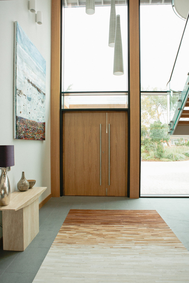 Design ideas for a contemporary front door in Devon with white walls, ceramic flooring, a double front door, a medium wood front door and feature lighting.