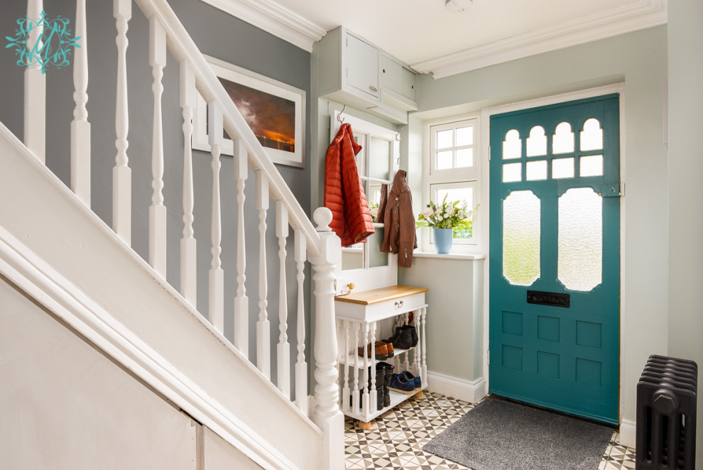 Idée de décoration pour une entrée de taille moyenne avec un couloir, un mur vert, un sol en carrelage de céramique, une porte simple, une porte bleue et un sol gris.