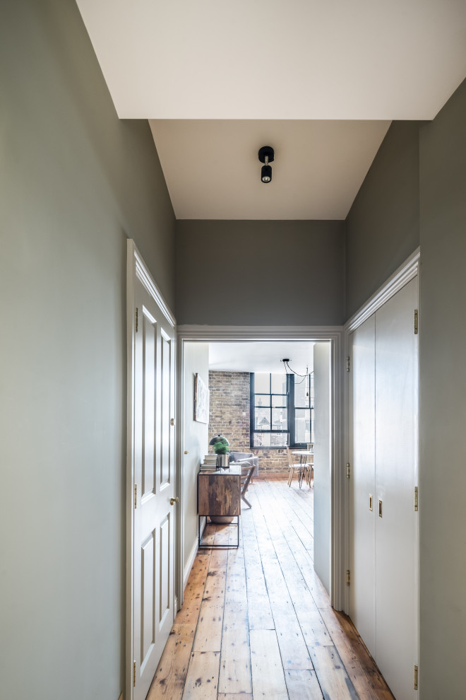 На фото: большая узкая прихожая в стиле лофт с серыми стенами, паркетным полом среднего тона, одностворчатой входной дверью, белой входной дверью и коричневым полом с