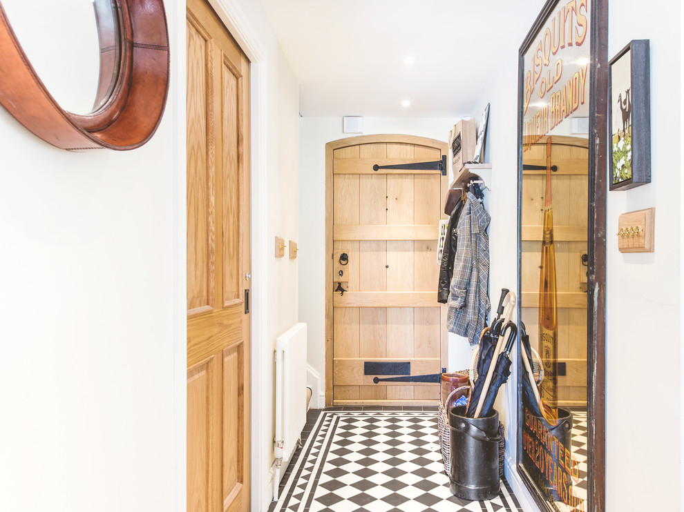 This is an example of a small traditional hallway in Berkshire with ceramic flooring, a single front door, a light wood front door and white walls.