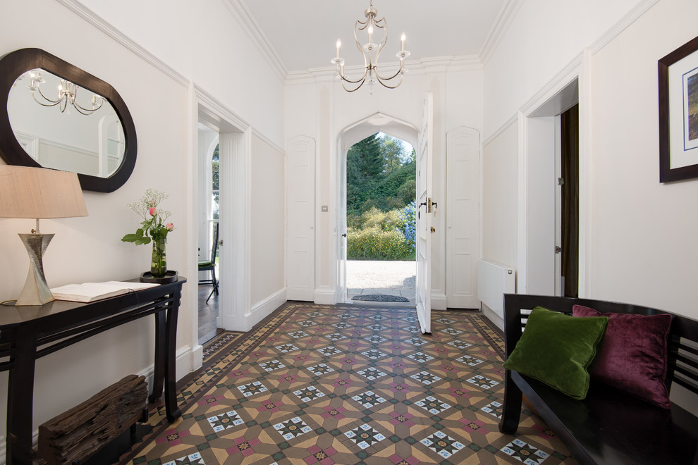 他の地域にあるお手頃価格の広いヴィクトリアン調のおしゃれな玄関ロビー (白い壁、磁器タイルの床、白いドア、マルチカラーの床) の写真