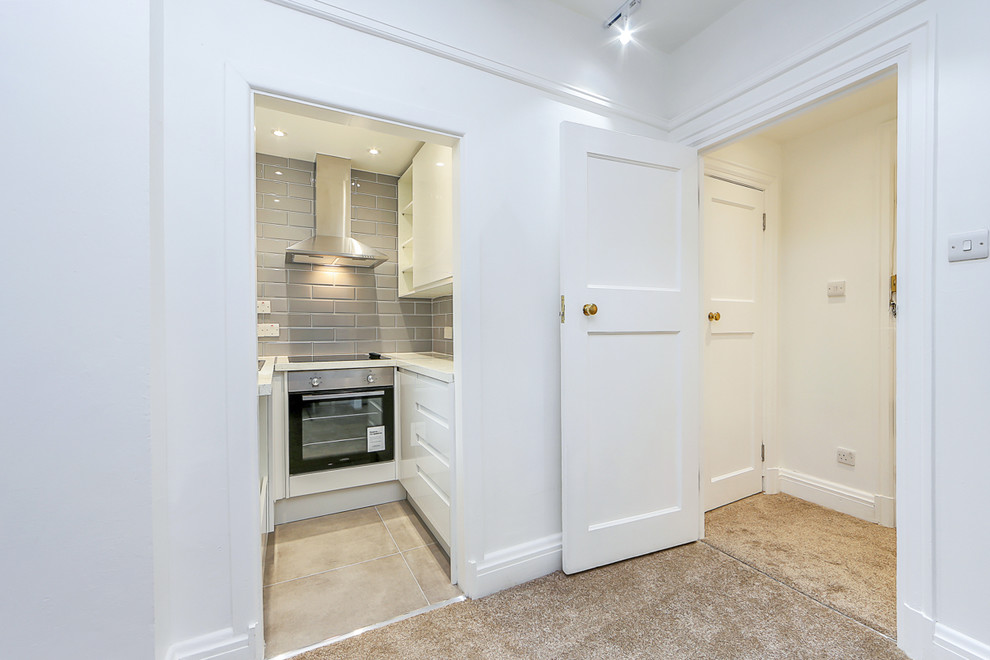Cette photo montre une petite porte d'entrée tendance avec un mur blanc, moquette, une porte simple, une porte blanche et un sol beige.