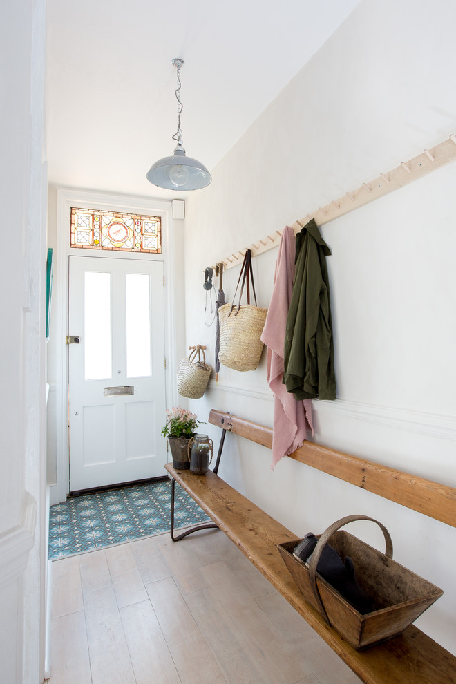 Modelo de hall clásico de tamaño medio con paredes blancas, suelo de madera clara, puerta simple, puerta blanca y suelo beige