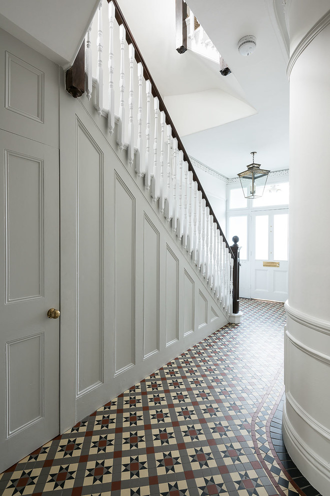 This is an example of a medium sized classic entrance in London with white walls, ceramic flooring, multi-coloured floors and feature lighting.