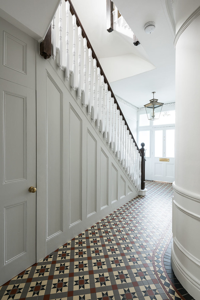 Example of a mid-sized classic ceramic tile and multicolored floor entryway design in London with white walls
