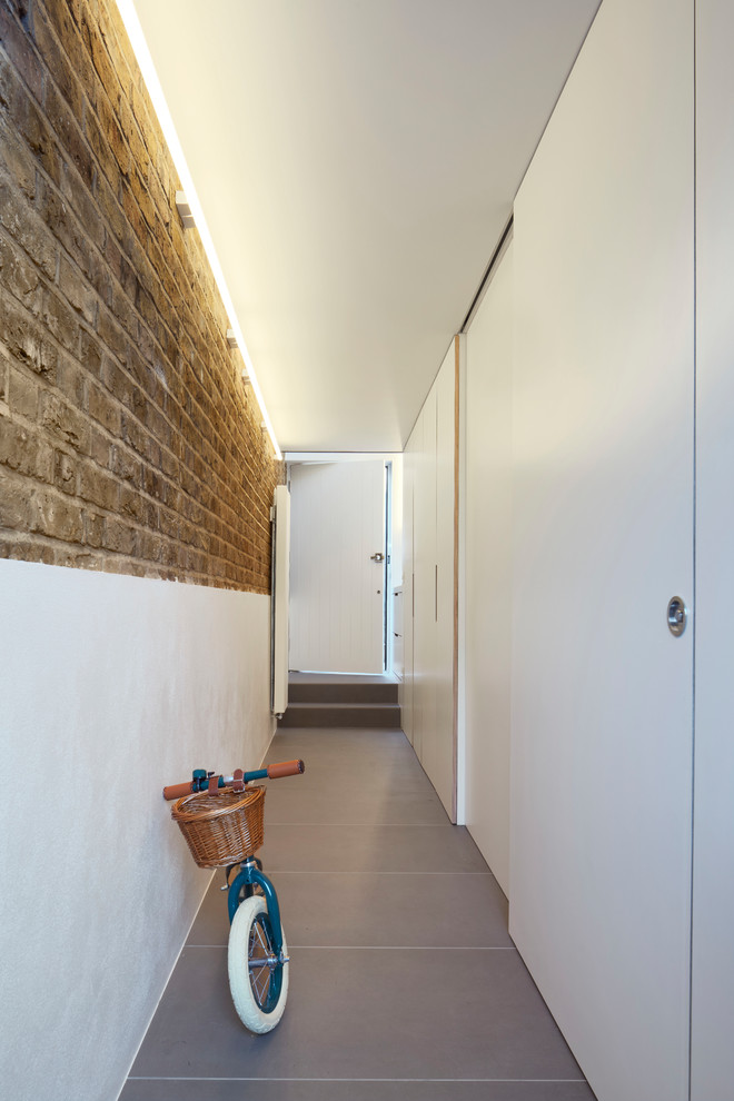 Exemple d'une petite porte d'entrée moderne avec un mur blanc, sol en béton ciré, une porte simple, une porte noire, un sol gris, un plafond voûté et un mur en parement de brique.