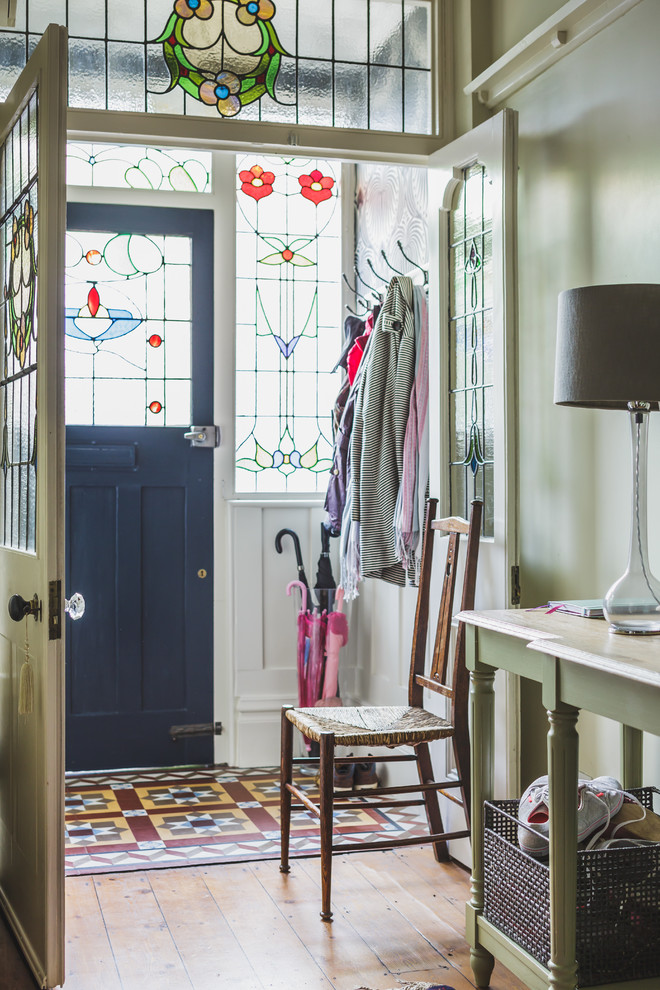Example of an ornate medium tone wood floor entryway design in Other with green walls and a black front door