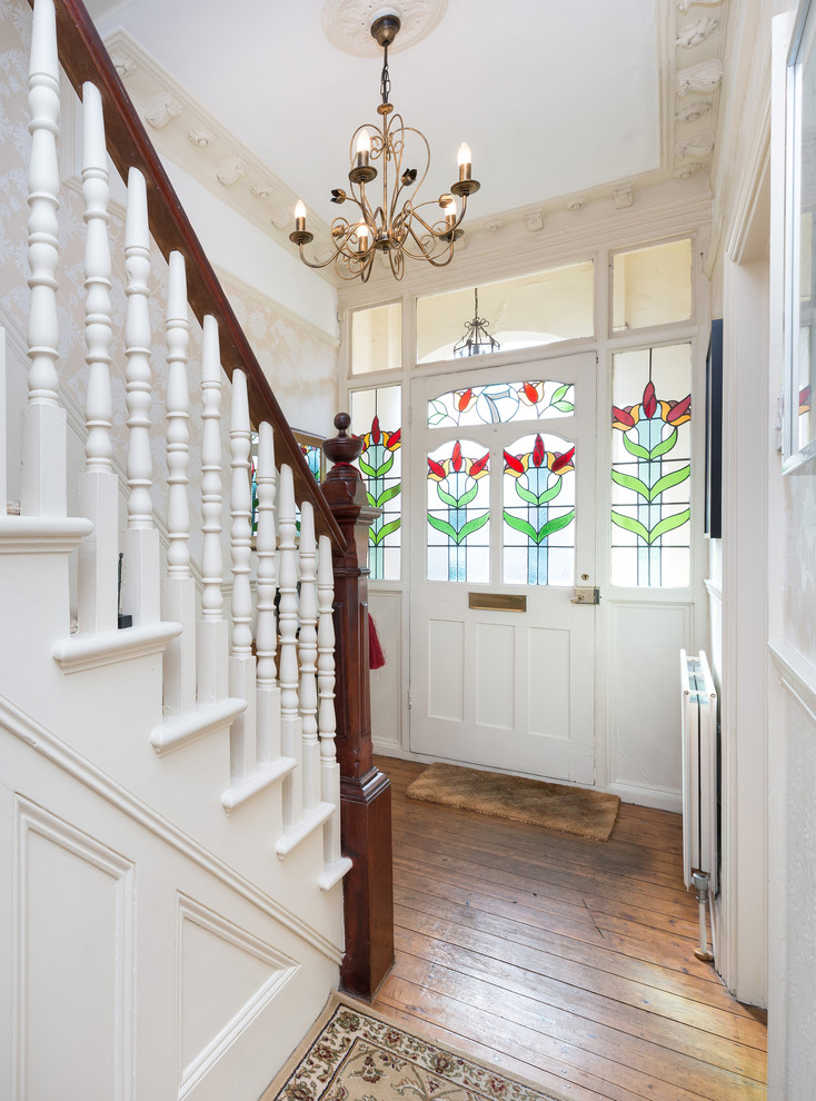 ロンドンにある小さなヴィクトリアン調のおしゃれな玄関ロビー (白い壁、無垢フローリング、白いドア) の写真
