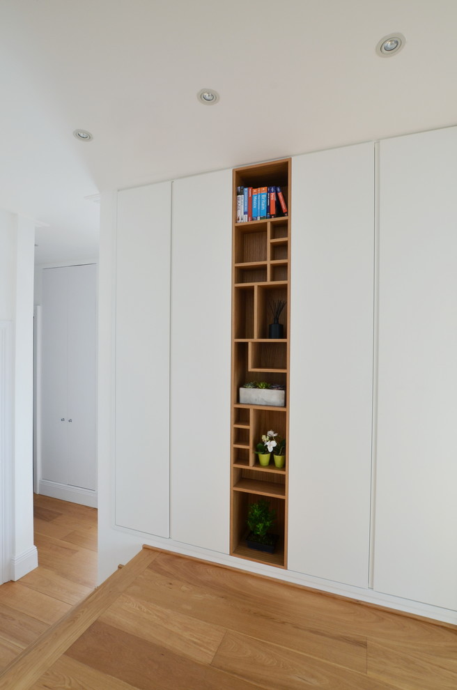 Immagine di un piccolo corridoio minimal con pareti bianche, parquet chiaro, una porta singola, una porta grigia e pavimento beige