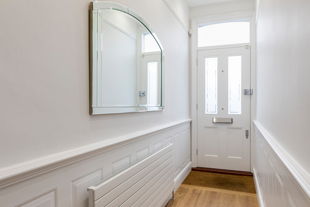 Idee per un piccolo corridoio design con pareti bianche, parquet chiaro, una porta singola, una porta bianca e pavimento marrone