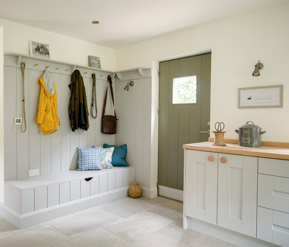 This is an example of a farmhouse boot room in West Midlands with white walls, a single front door, a green front door and beige floors.
