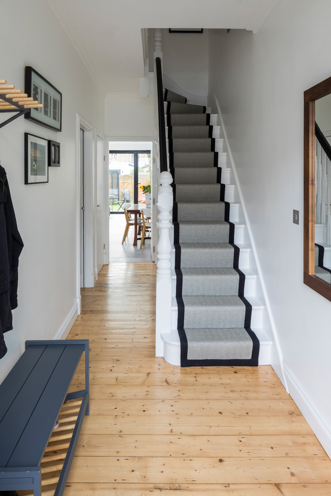 Photo of a medium sized contemporary hallway in London with white walls, light hardwood flooring, a single front door, a blue front door and brown floors.