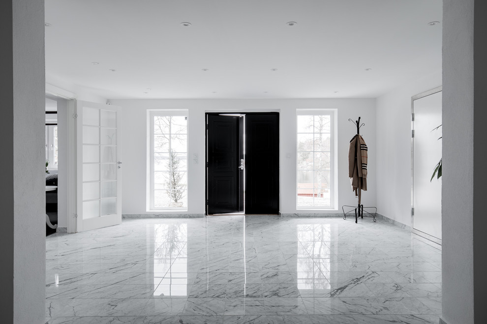 Inredning av en minimalistisk entré, med marmorgolv, en dubbeldörr och en svart dörr