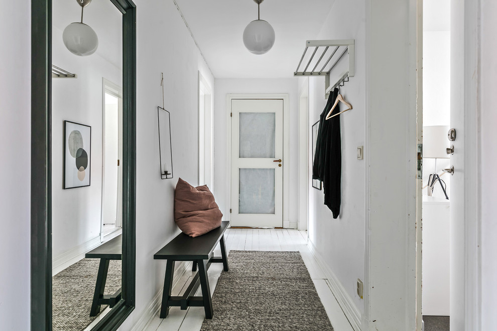 Esempio di un corridoio scandinavo con pareti bianche, pavimento in legno verniciato, una porta singola, una porta bianca e pavimento bianco