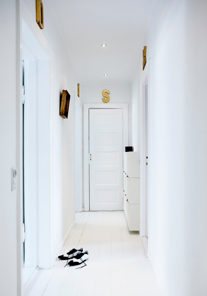 This is an example of a medium sized scandinavian front door in Copenhagen with white walls, light hardwood flooring, a single front door and a white front door.