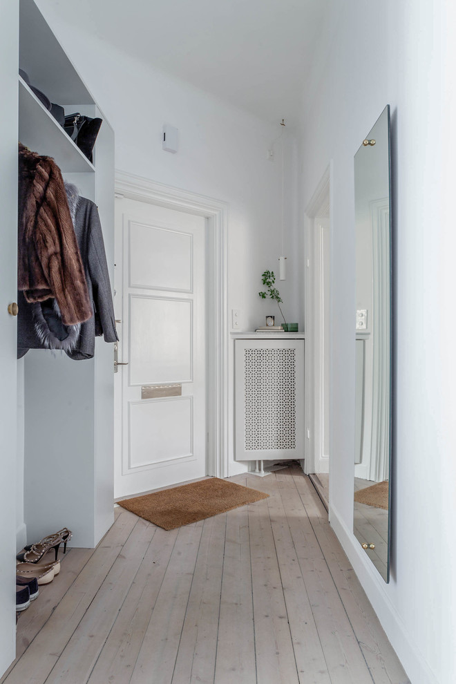 Exempel på en mellanstor minimalistisk entré, med vita väggar och ljust trägolv