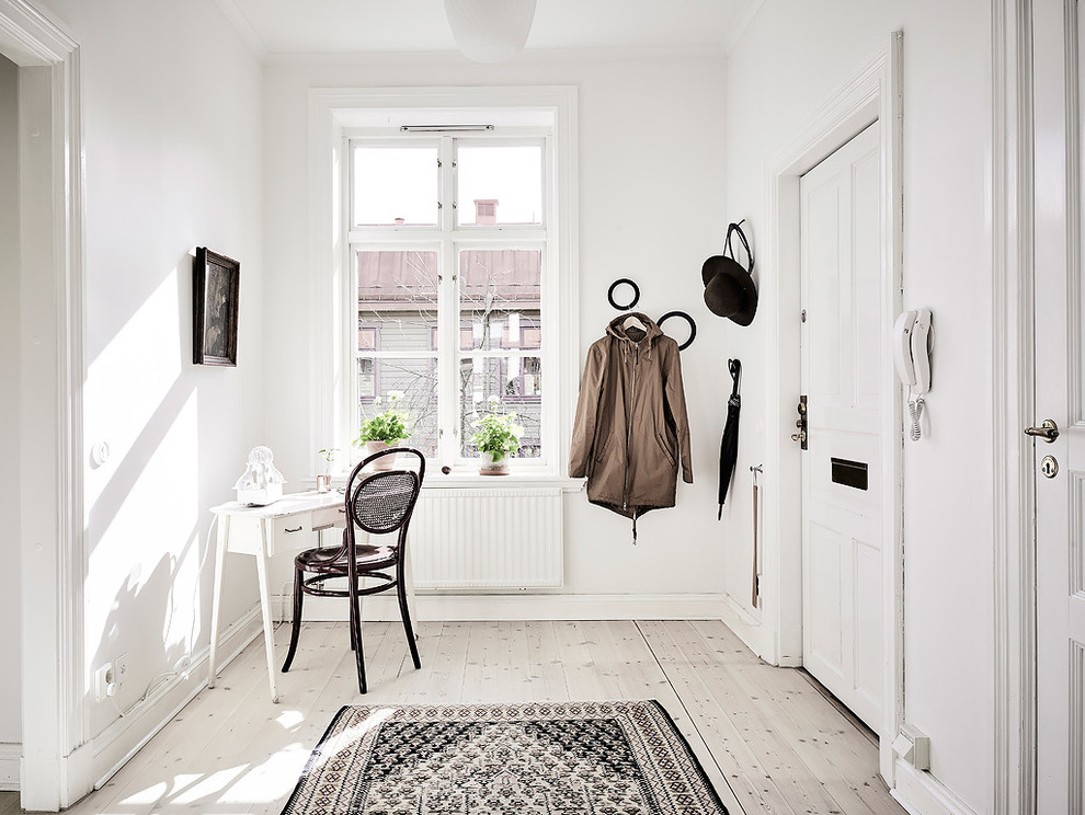 Idéer för mellanstora minimalistiska entréer, med vita väggar och ljust trägolv
