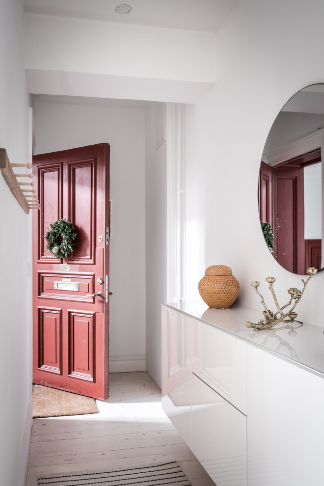 На фото: входная дверь в скандинавском стиле с белыми стенами, светлым паркетным полом, одностворчатой входной дверью, красной входной дверью и бежевым полом
