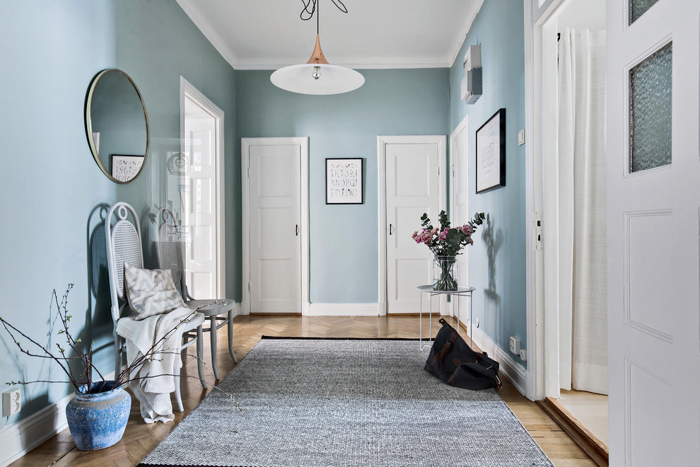 На фото: узкая прихожая среднего размера в скандинавском стиле с синими стенами, светлым паркетным полом и одностворчатой входной дверью