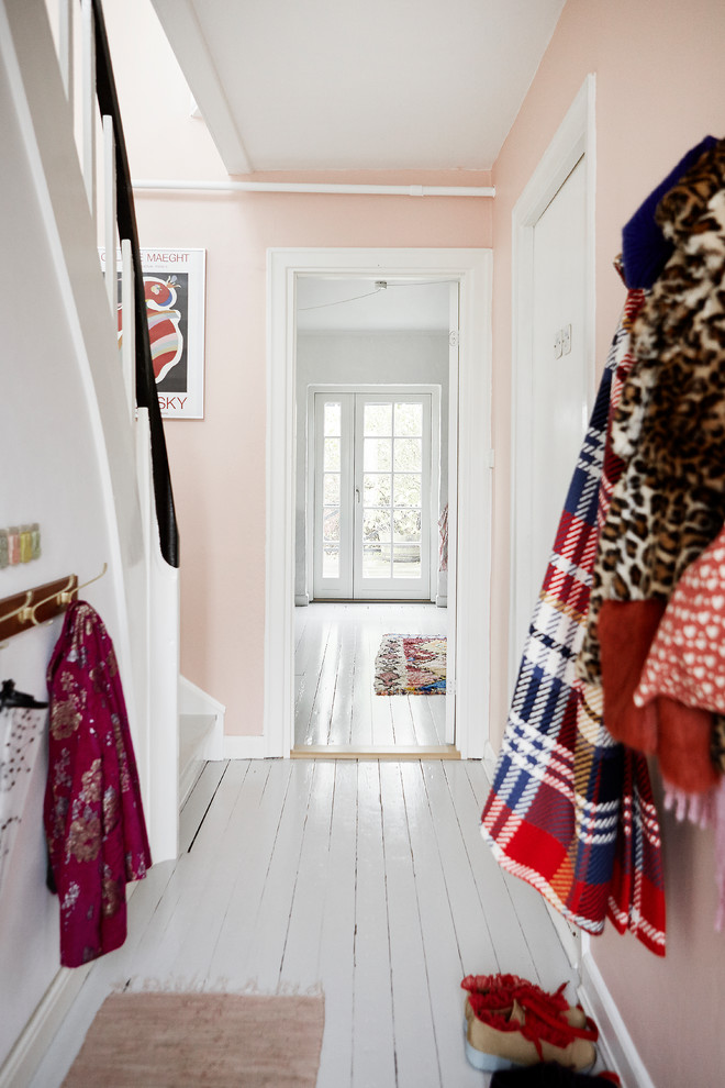 オーフスにある小さな北欧スタイルのおしゃれな玄関 (ピンクの壁、塗装フローリング、白い床) の写真