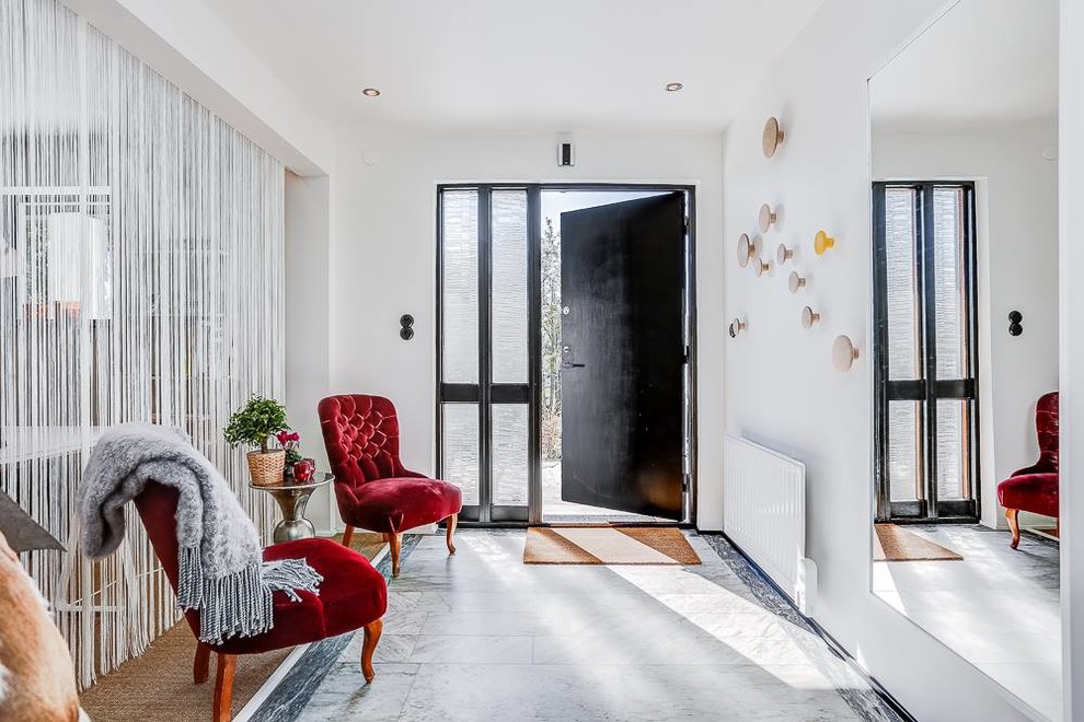 This is an example of a medium sized contemporary entrance in Stockholm with white walls, limestone flooring, a single front door and a dark wood front door.