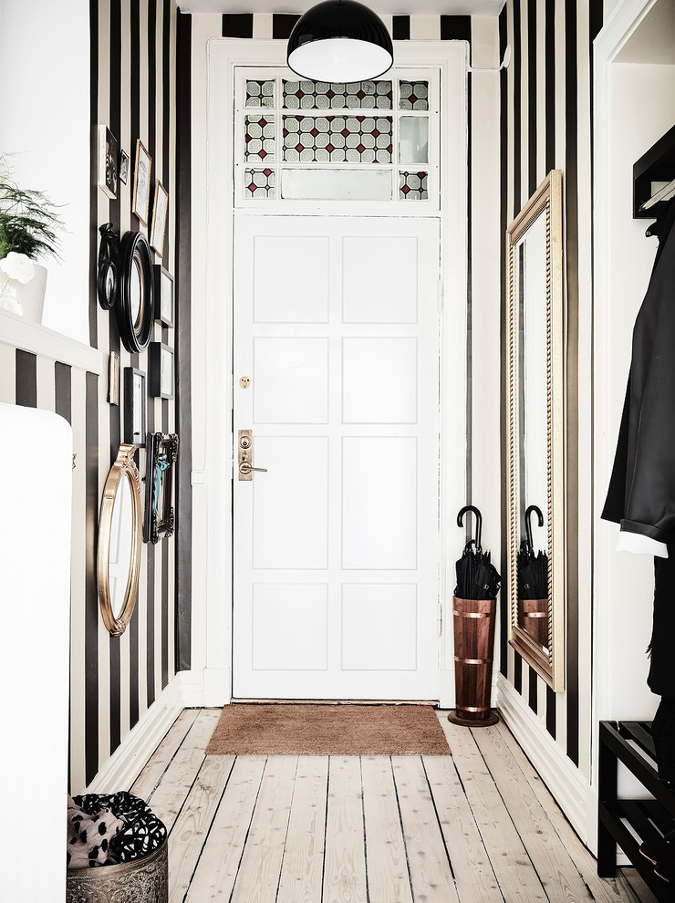 ヨーテボリにある高級な北欧スタイルのおしゃれな玄関 (白い壁、淡色無垢フローリング) の写真