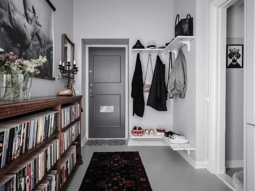 На фото: фойе в скандинавском стиле с белыми стенами, деревянным полом, одностворчатой входной дверью, серой входной дверью и серым полом с