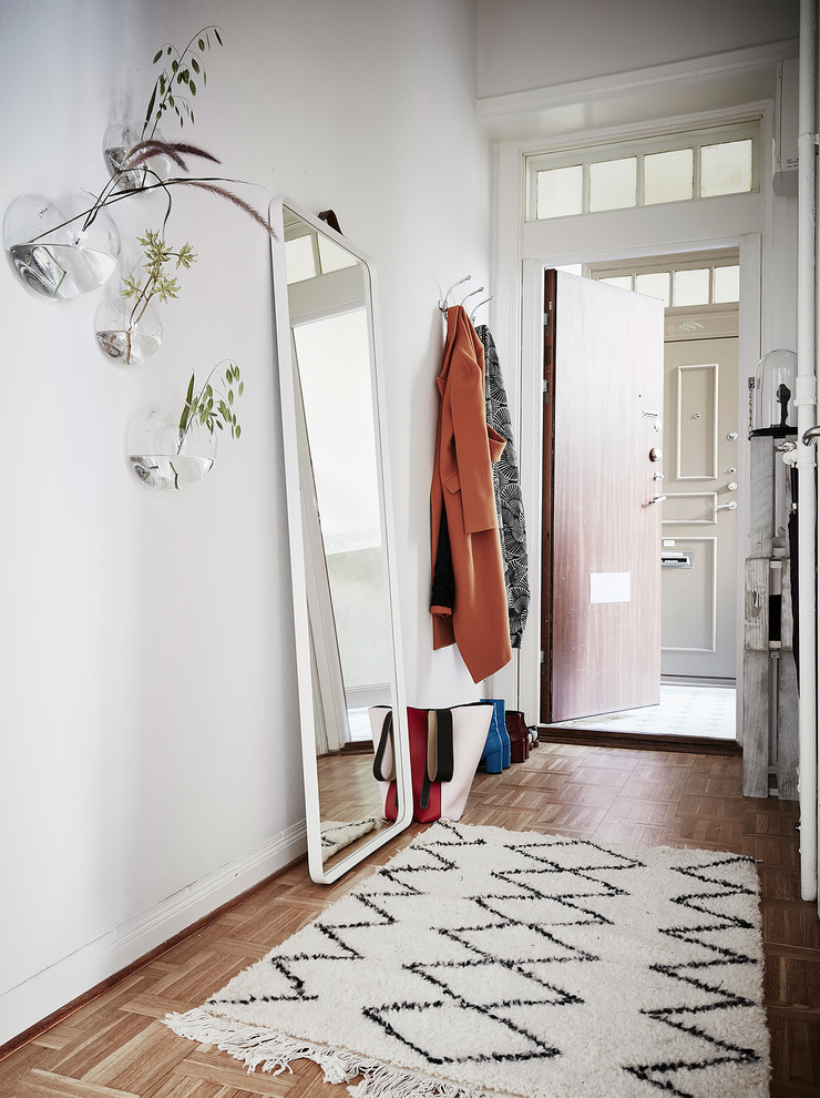 Diseño de entrada nórdica pequeña con paredes blancas, suelo de madera en tonos medios y suelo marrón
