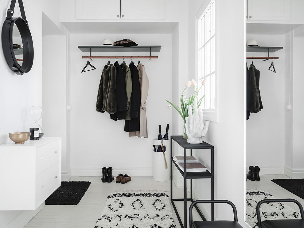 Photo of a scandi boot room in Gothenburg with white walls, painted wood flooring and white floors.