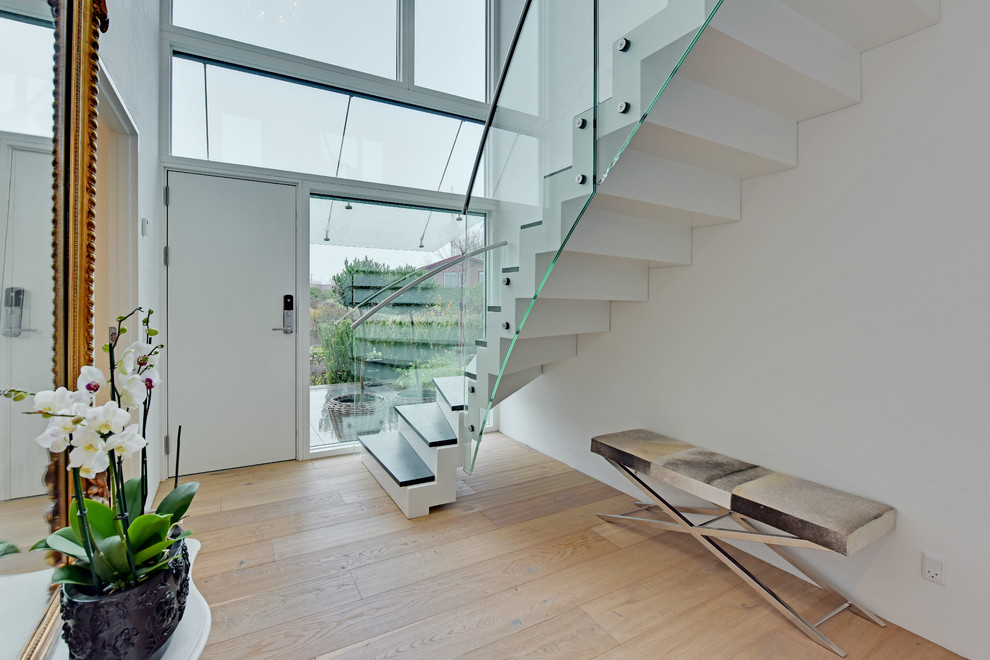 Contemporary entrance in Aarhus with white walls, light hardwood flooring and a white front door.