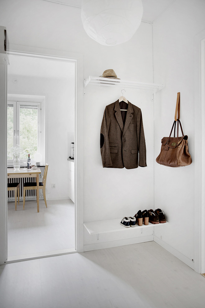 Exempel på ett minimalistiskt kapprum, med vita väggar, ljust trägolv och vitt golv